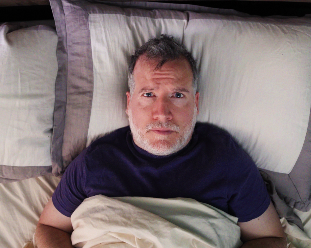Mann liegt wach im Bett