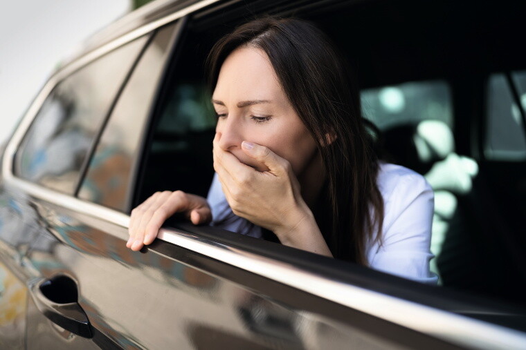 Frau im Auto hält sich Hand vor den Mund.