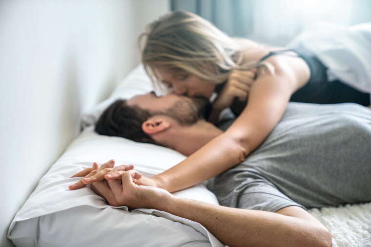 Mann und Frau küssen sich im Bett. Mann und Frau küssen sich im Bett.