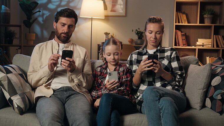 Mann, Mädchen und Frau sitzen auf dem Sofa und haben jeweils ein Smartphone in der Hand.