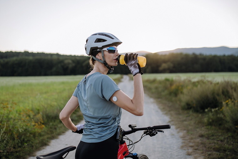 Frua mit Fahrradhelm trinkt.