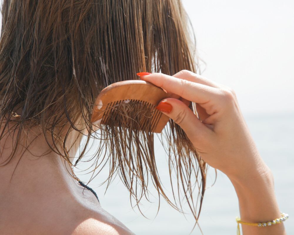 Frau kämmt sich die feuchten Haare am Strand. Frau kämmt sich die feuchten Haare am Strand.