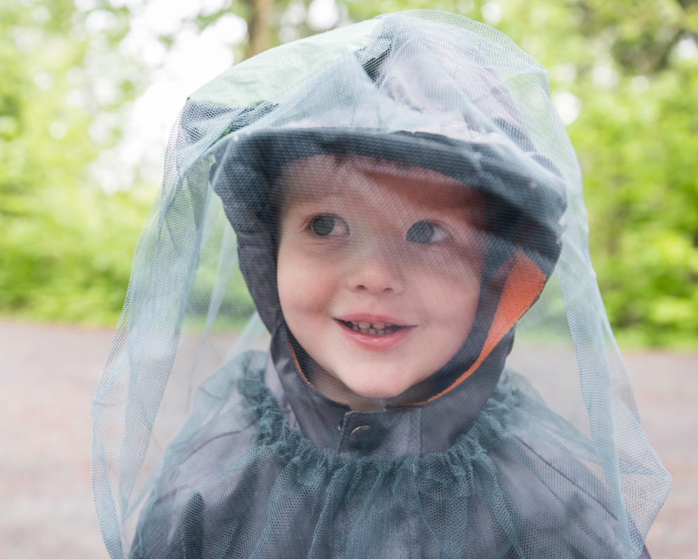 Kind mit Insektenschutznetz auf dem Kopf