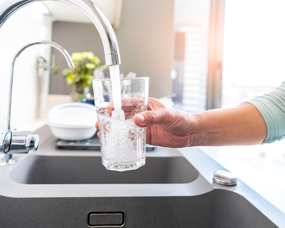 Glas unterm Wasserhahn mit Wasser befüllen