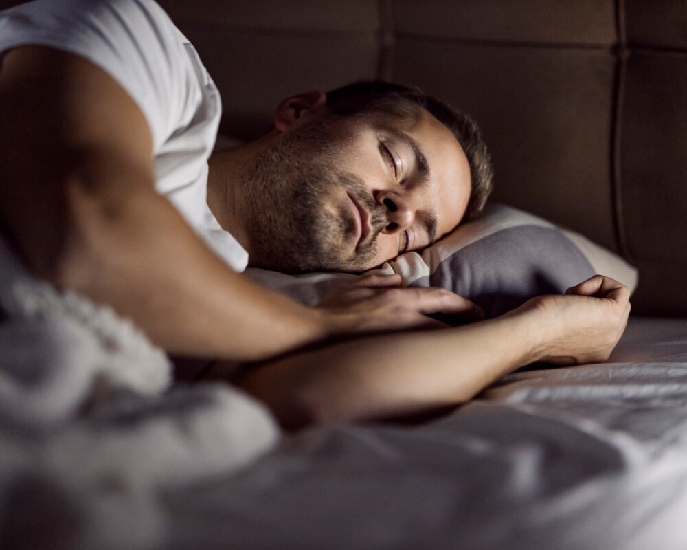 Mann schläft im Bett.