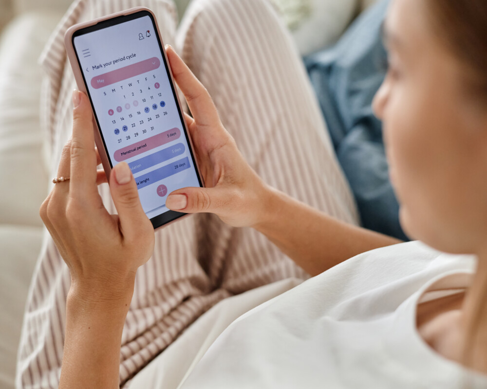 Frau mit Zykluskalender auf dem Handy