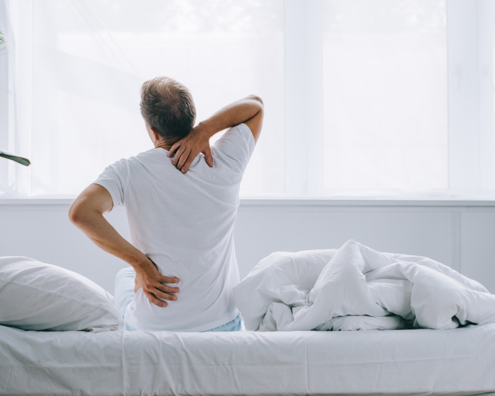 Mann fasst sich an den unteren Rücken und an den Nacken.