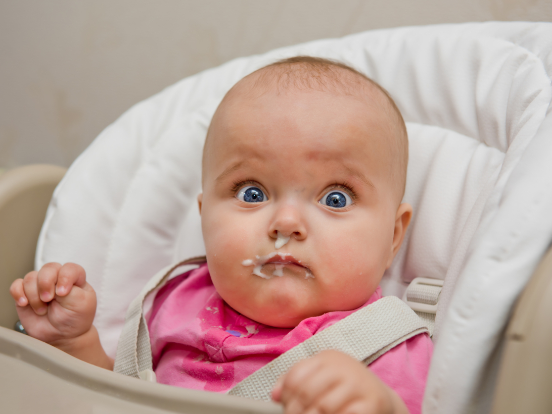 Baby mit breiverschmiertem Gesicht schaut in die Kamera.