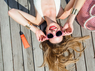 Frau mit Sonnenbrille und Sonnencreme