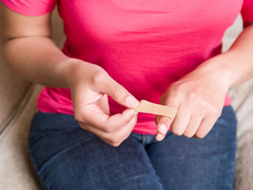 Frau behandelt verletzten Finger mit Pflaster.