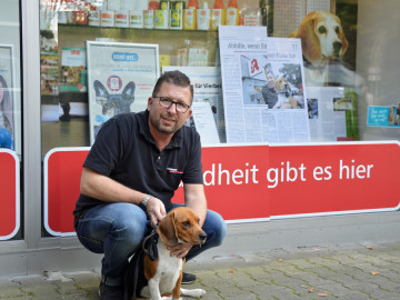 Apotheker Alexander Jaksche mit seinem Beagle vorm Schaufenster.