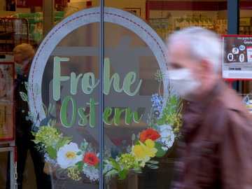 Tür mit "Frohe Ostern" und Passant mit Mundschutz