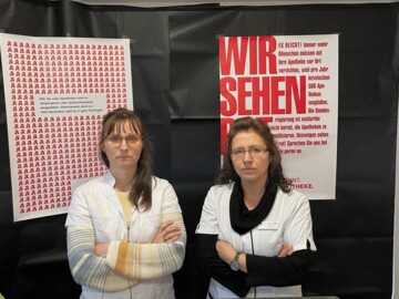 Anja Huhle (rechts) und eine Mitarbeiterin vor dem Protestplakat zur Aktion #wirsehenrot