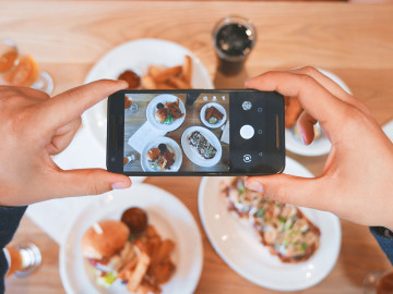 Verschiedene Tellergerichte, die mit dem Smartphone fotografiert werden