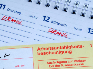 Arbeitsunfähigkeitsbescheinigung liegt auf Kalender
