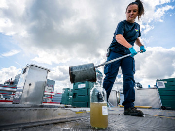 Mitarbeiterin in der Kläranlage entnimmt Abwasserprobe