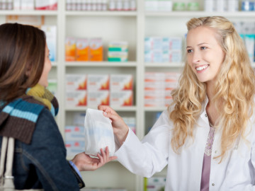 Apothekerin gibt Tüte mit Einkauf an die Kundin
