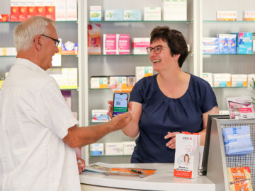 Kunde und Apothekenmitarbeiterin mit Smartphone