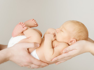 Neugeborenes schläft in den Händen seiner Eltern