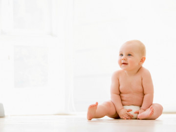 Baby mit Windel sitzt auf dem Boden