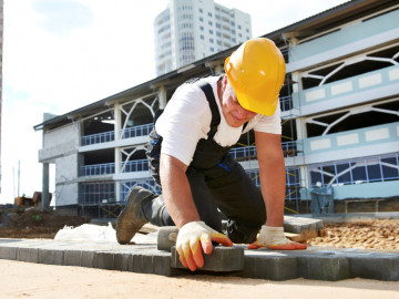 Handwerker im T-Shirt verlegt Pflastersteine