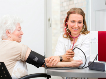 Ärztin misst Seniorin in der Praxis den Blutdruck