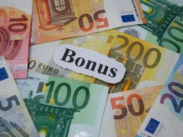 Auf verschiedenen Euroscheinen liegt ein Zettel mit dem Wort Bonus