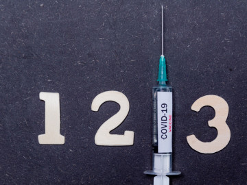 Ziffern 1,2 und 3 mit einer Spritze mit Beschriftung COVID-19 Vaccine