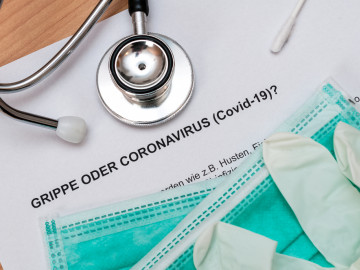 Paper „Grippe oder Corona“ mit Stethoskop und Einmalmasken und Einmalhandschuhen