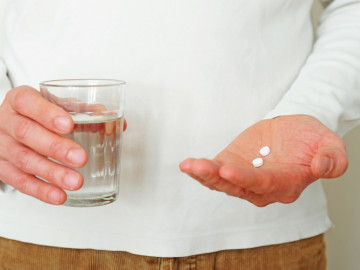 Mann mit Wasserglas und zwei Tabletten