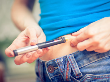 Frau, die sich mit einem Pen Insulin in die Bauchfalte injiziert.