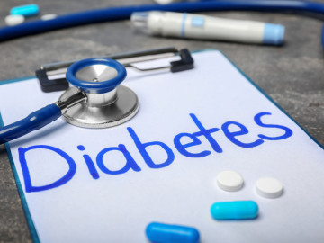 Komposition aus dem Wort „Diabetes“, Stethoskop, Tabletten und Kapseln auf einem Tisch