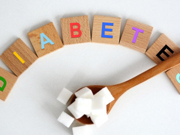 Zuckerwürfel auf einem Holzlöffel; Das Wort "Diabetes" gelegt aus kleinen Holztäfelchen