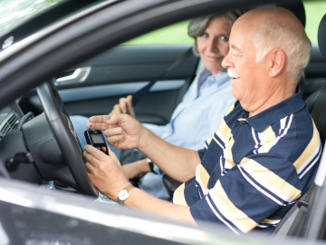 Paar im Auto; Mann am Steuer misst Blutzuckerwert