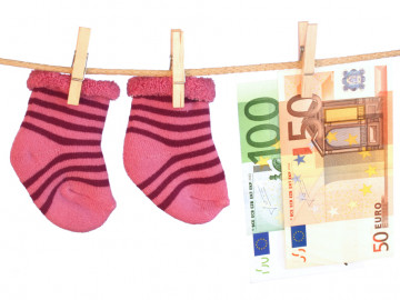 Babysöckchen und Euroscheine hängen auf einer Wäscheleine
