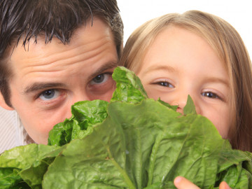 Vater und Tochter mit einem Kopfsalat vor dem Gesicht
