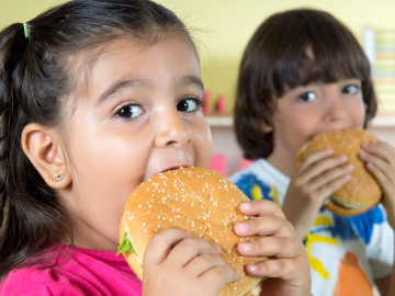 Mädchen und Junge beißen in einen Hamburger