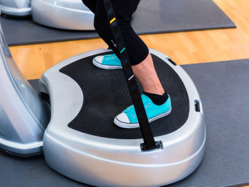 Frau beim Sport auf Power Plate im Fitnessstudio