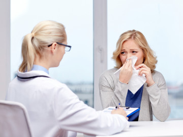 Frau mit Grippe im Gespräch mit einer Ärztin