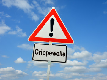 Signalschild mit Ausrufezeichen und weiterem Schild mit Aufschrift Grippewelle