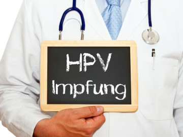 Arzt hält Tafel mit Aufschrift HPV Impfung