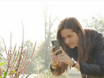 Frau fotografiert mit dem Handy eine Pflanze