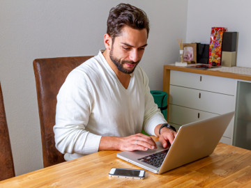 Mann mit Laptop am Küchentisch