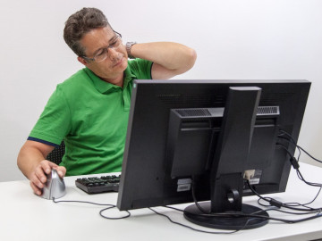 Mann vor dem Computer reibt sich den Nacken