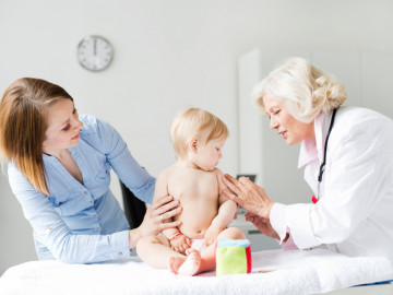 Baby wird von Ärztin geimpft. Mutter steht links daneben.