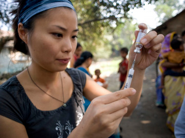 Asiatische Frau zieht Spritze mit Impfstoff auf