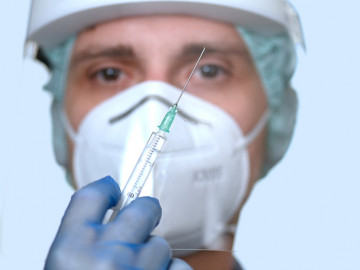 Symbolbild Corona-Impfstoff: Mediziner mit Maske und Spritze