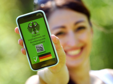 Frau hält Smartphone mit Impfnachweis in die Kamera