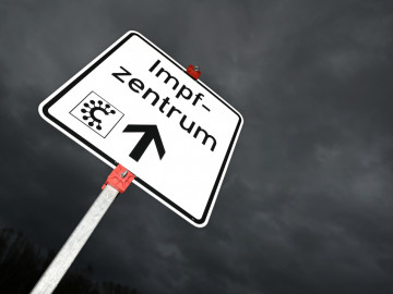 Hinweisschild mit der Aufschrift "Impfzentrum" und einem Covid-Logo