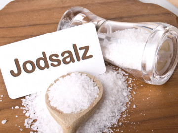Umgekippter Salzstreuer, Kochlöffel mit Salz und Schild Jodsalz